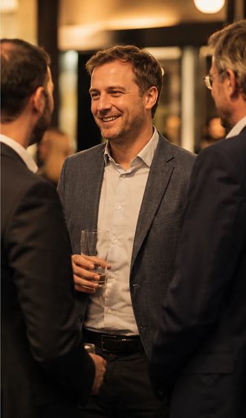 A man laughs and talks inside a group of people